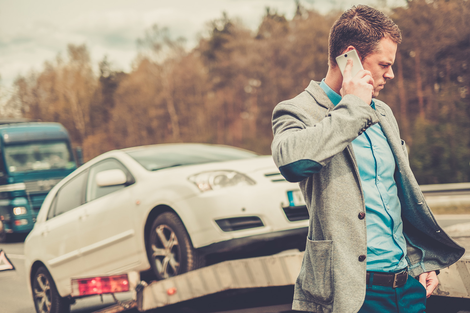 Man calling while tow truck picking up his broken car